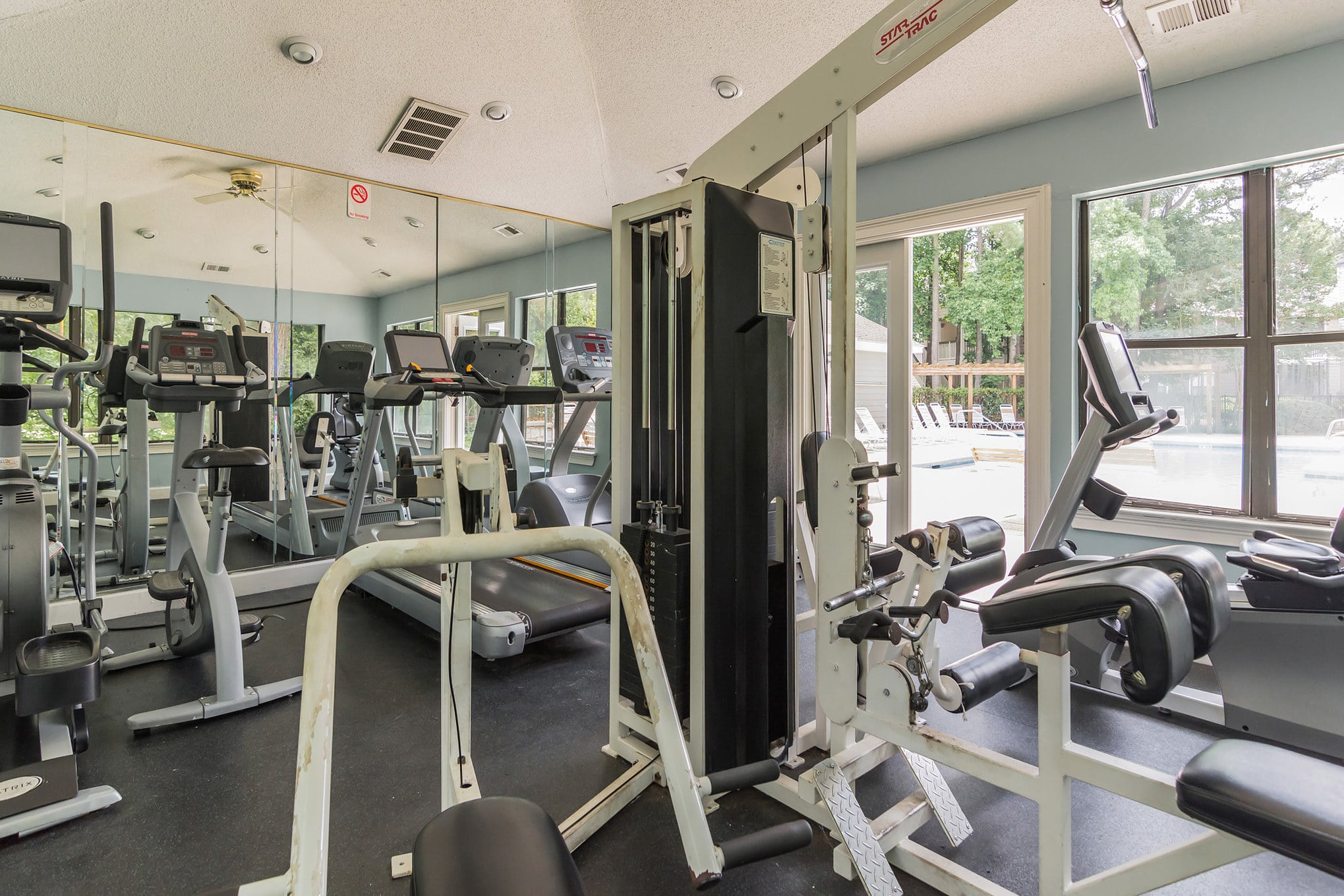 A gym room with exercise equipment and mirrors, located within a Two Bedroom Apartment.